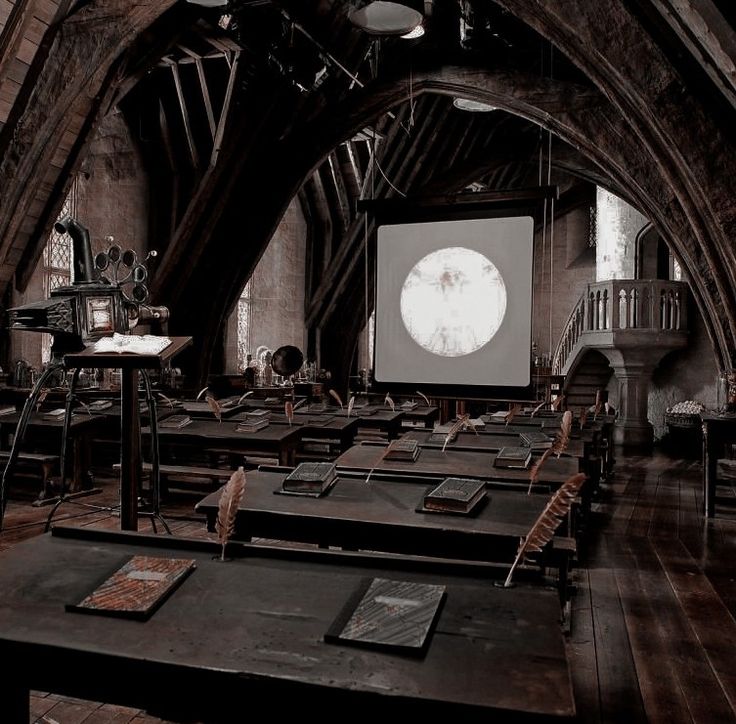 an empty room with tables and chairs in front of a projector screen on the wall