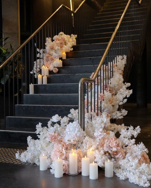 flowers and candles are on the ground in front of stairs with railings leading up to them