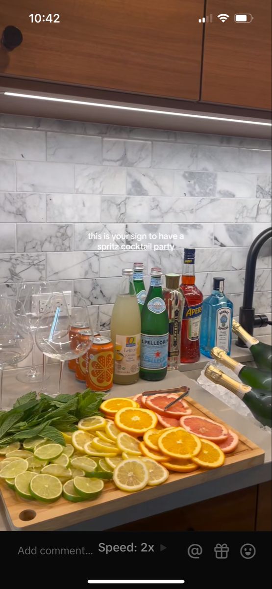 the kitchen counter is covered with many different types of drinks and fruit, including oranges