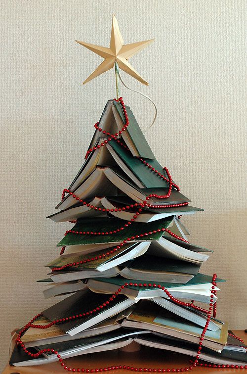 a christmas tree made out of books with a star hanging from it's top