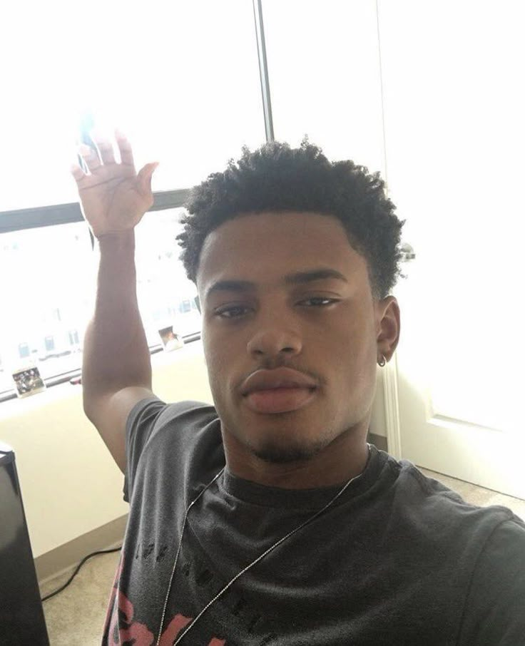 a young man sitting in front of a computer holding his hand up to the camera