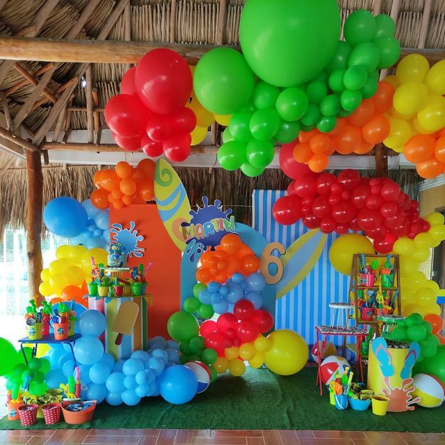 a bunch of balloons are hanging from the ceiling in front of a birthday party table