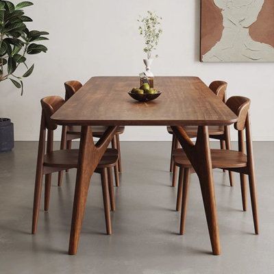 a wooden table with chairs around it and a potted plant in the corner next to it