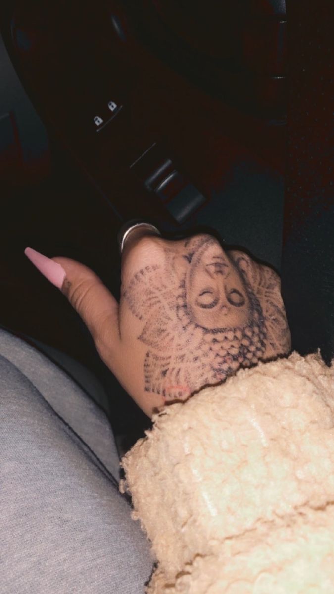 a person's hand with tattoos on it sitting in a car next to a steering wheel