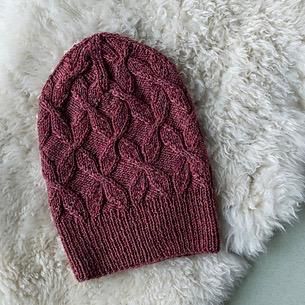 a red knitted hat laying on top of a white fur