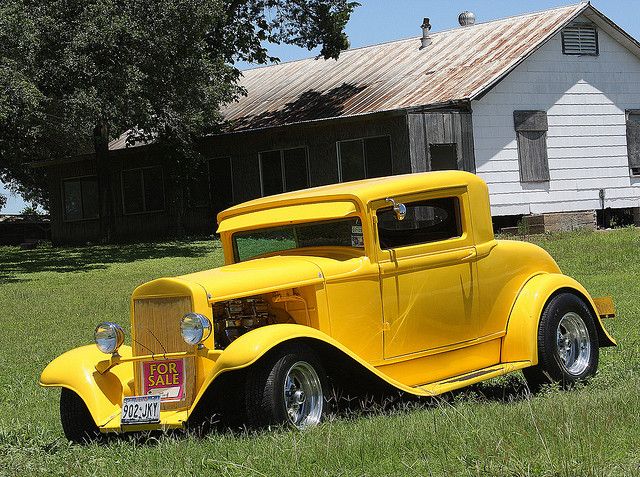 an old yellow car is parked in the grass