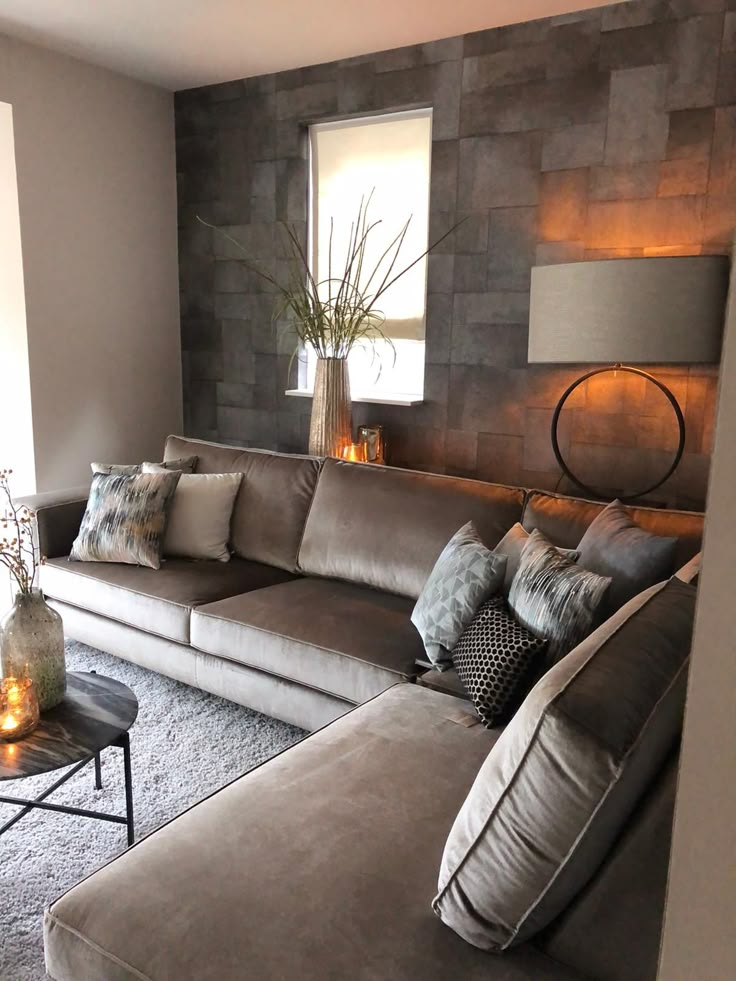 a living room filled with lots of furniture next to a wall covered in stone tiles