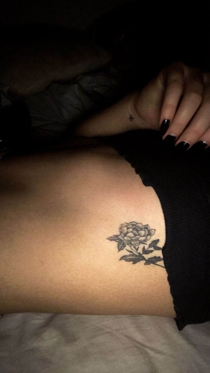 a woman laying in bed with a tattoo on her thigh