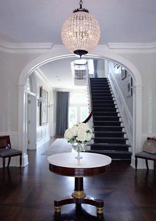 the foyer is decorated with white flowers and chandelier