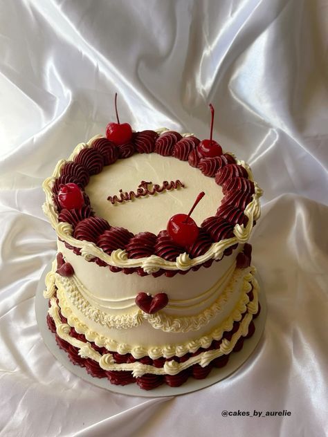 a three layer cake with cherries and the word happy written on top is sitting on a white cloth