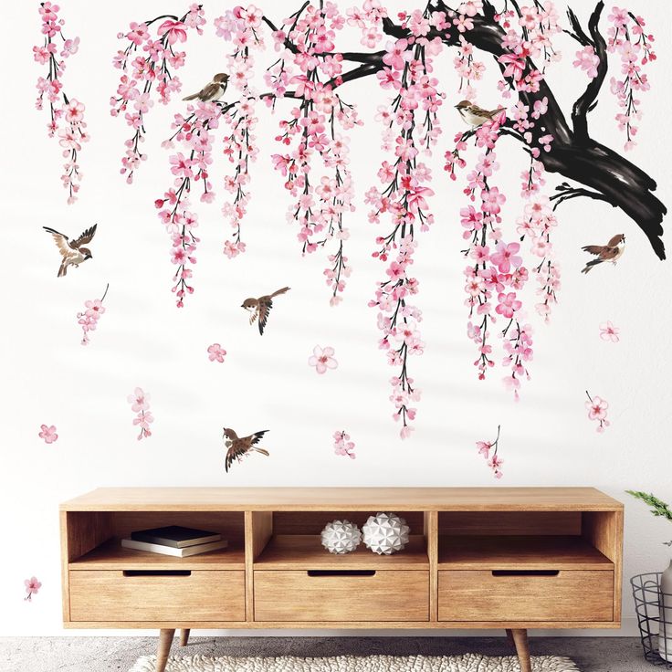 wall decals with pink flowers and birds flying over the branches in front of it