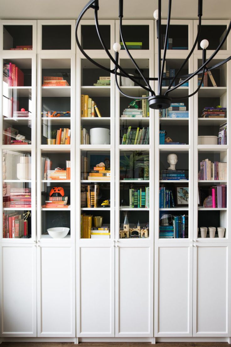 a chandelier hanging from the ceiling in front of white bookcases