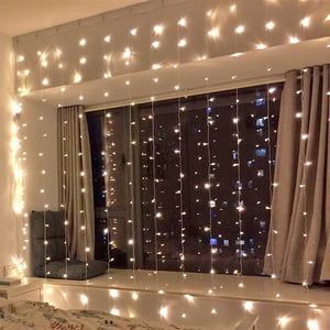 a bedroom with lights hanging from the ceiling and curtains on the window sill over the bed