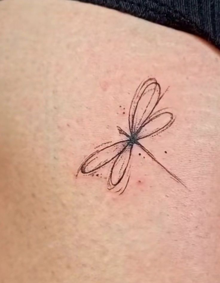 a small dragonfly tattoo on the back of a woman's left ribcage