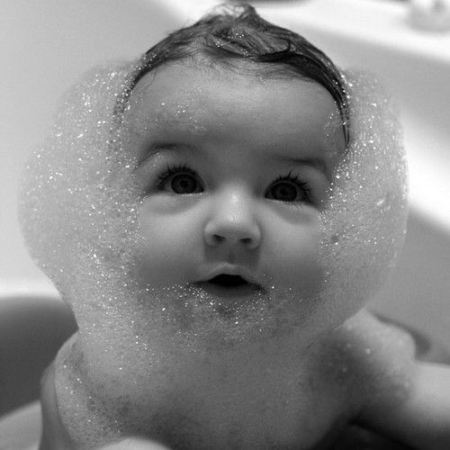 a baby in the bathtub with soap on his face