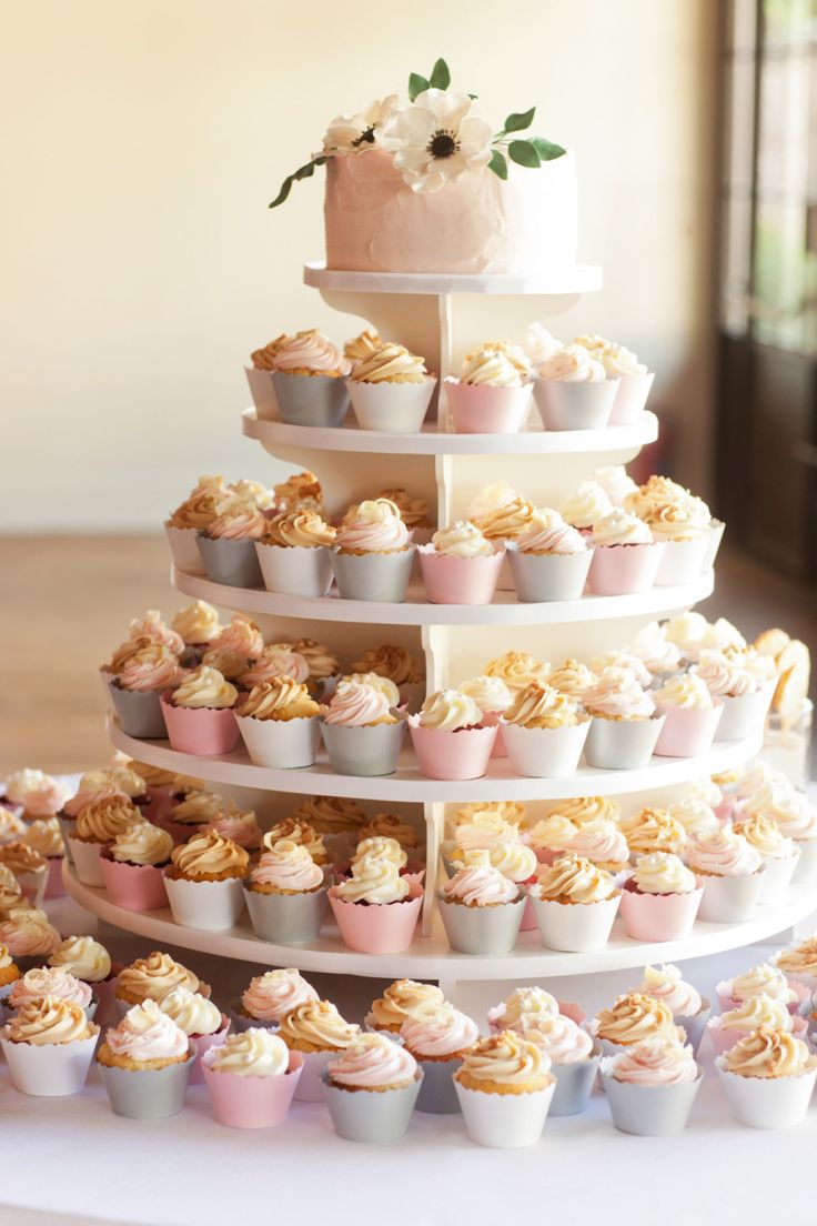 a tiered cake with cupcakes on it