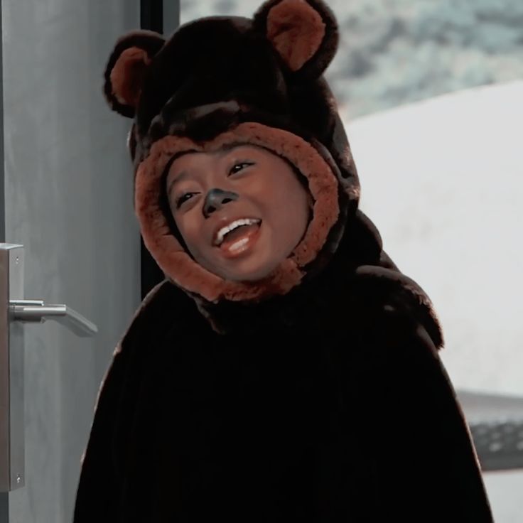 a woman wearing a bear costume standing in front of a door with her mouth open