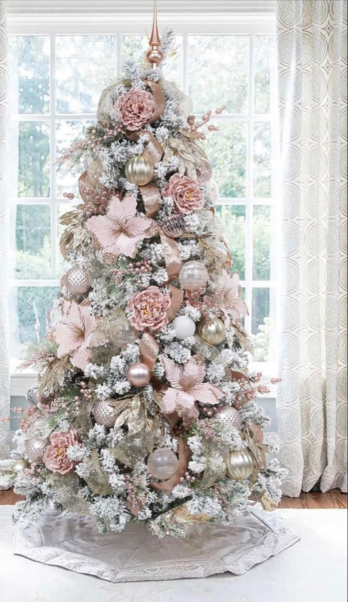 a white christmas tree with pink and gold ornaments in front of a large windowsill