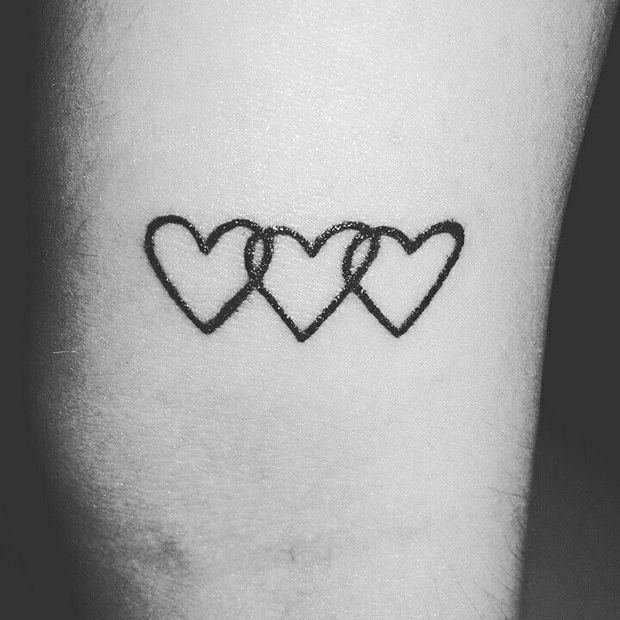 three hearts tattoo on the left inner arm, with one heart drawn in black ink