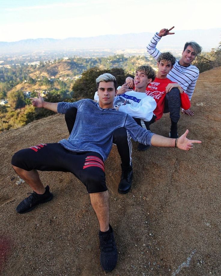 four young men are posing on top of a hill