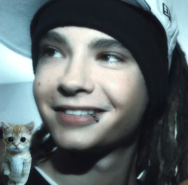 a man with dreadlocks and a cat in front of him smiling at the camera