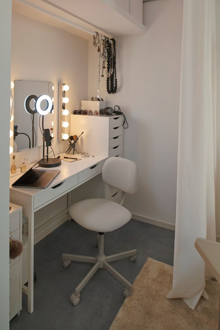 a white desk and chair in a small room with lights on the wall above it