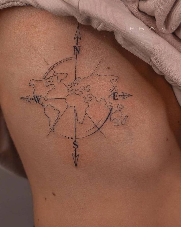 a woman's back with a compass tattoo on her left side ribcage