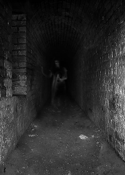 a person sitting in the middle of a dark tunnel