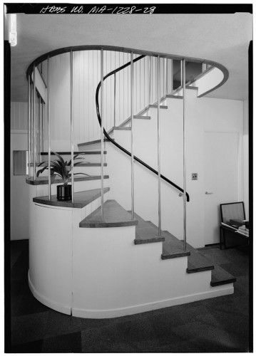 a black and white photo of a spiral staircase in an office building with carpeted flooring