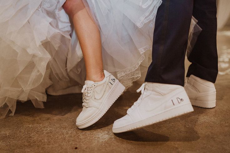 a bride and groom's feet in white sneakers with tulle skirt on their wedding day