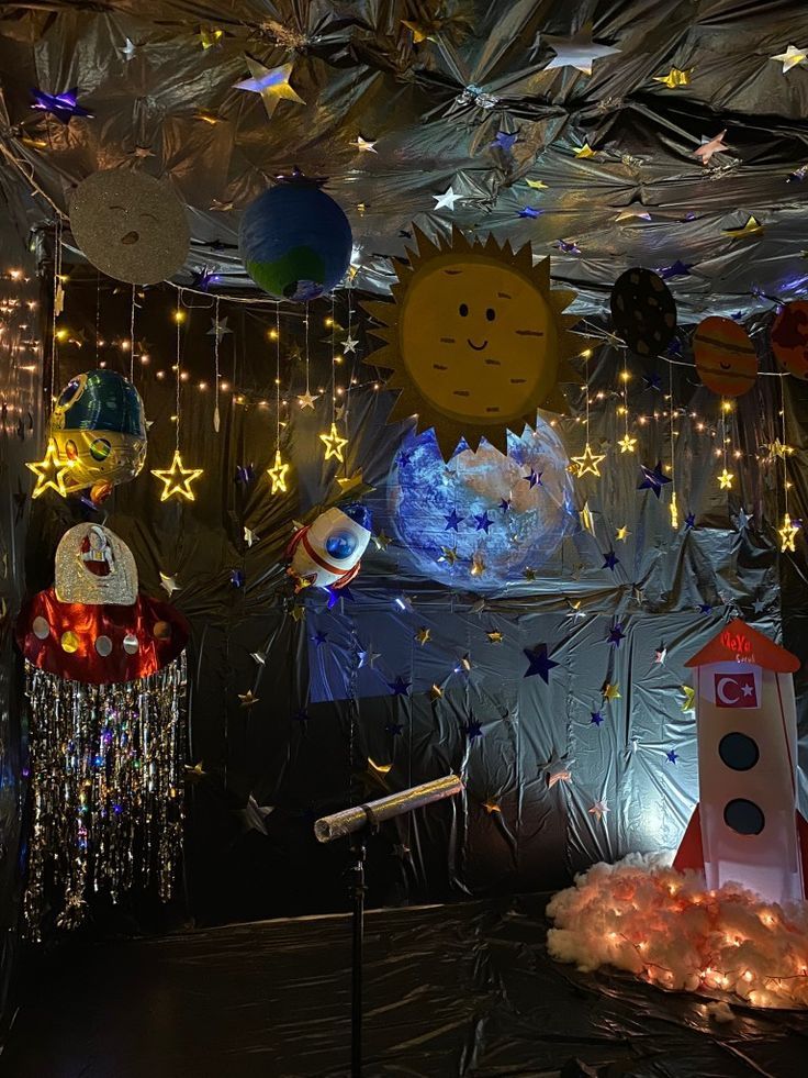 an indoor space themed party with lights and decorations on the ceiling, including stars, moon, and other objects