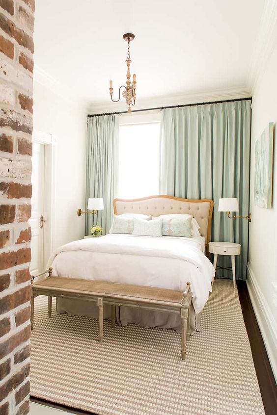 a bedroom with brick walls and a bed in the corner, along with a chandelier