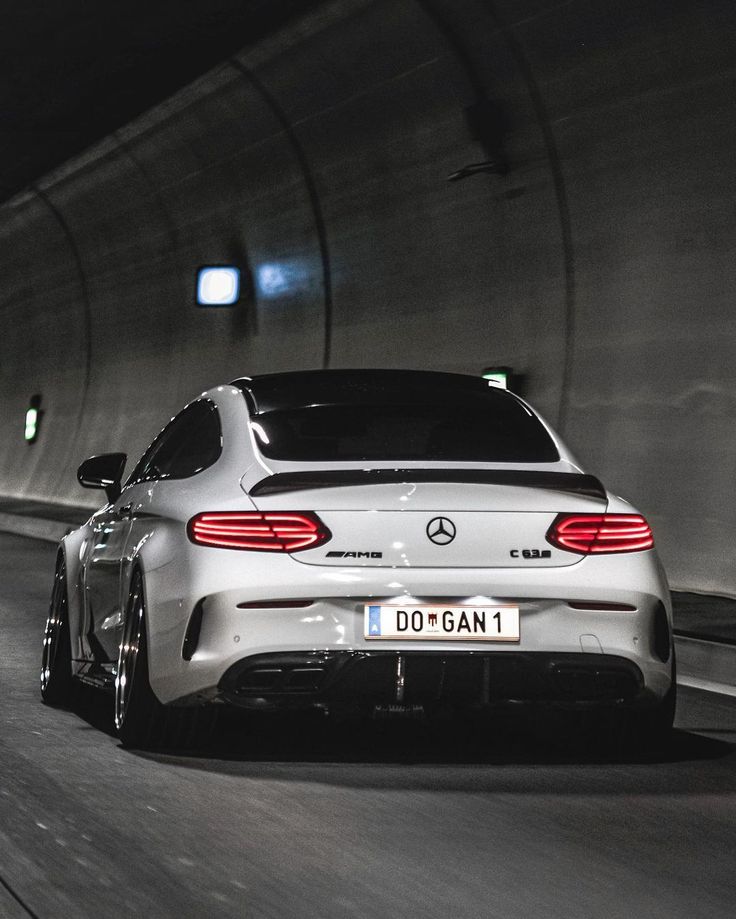 the rear end of a white car driving through a tunnel