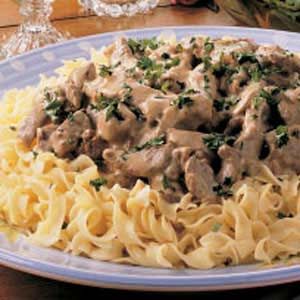 a plate of pasta with meat and gravy on it sitting on a table