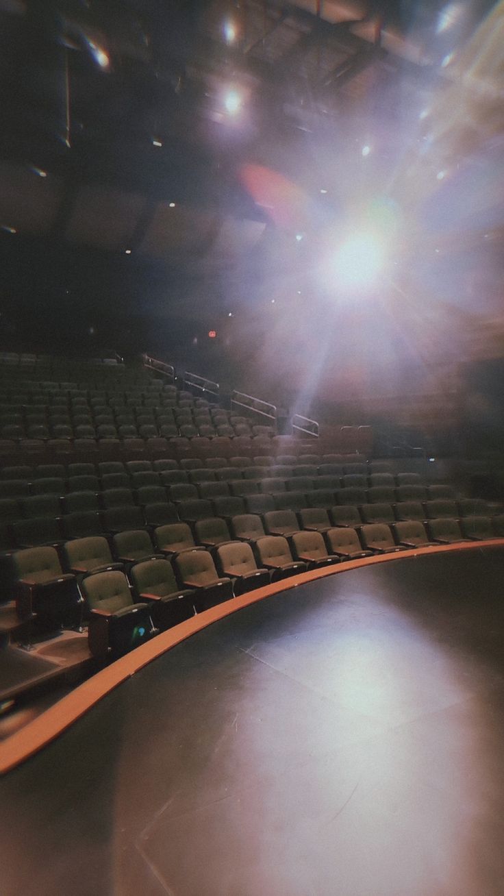 an empty auditorium with rows of seats and bright light coming from the ceiling in the background