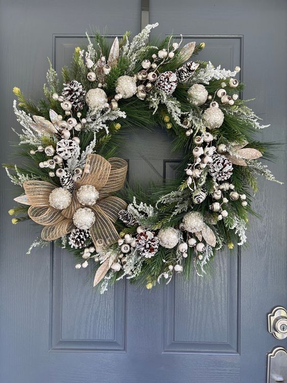 a wreath on the front door is decorated with white flowers and greenery as well as pine cones