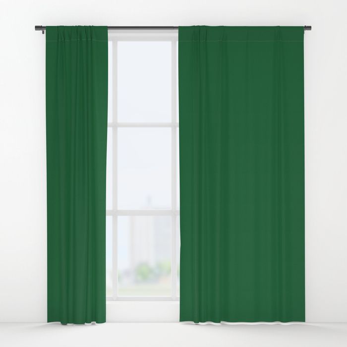 a green curtain hanging in front of a window with white walls and windowsills