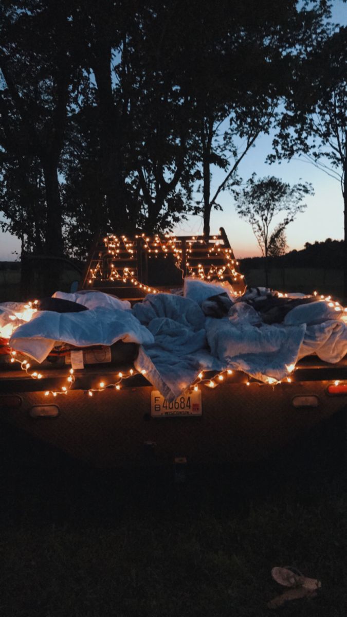 a truck is covered with blankets and lights in the back yard at night or dawn