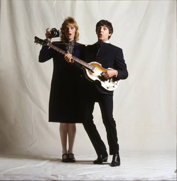 two people are holding guitars and posing for a photo in front of a white background