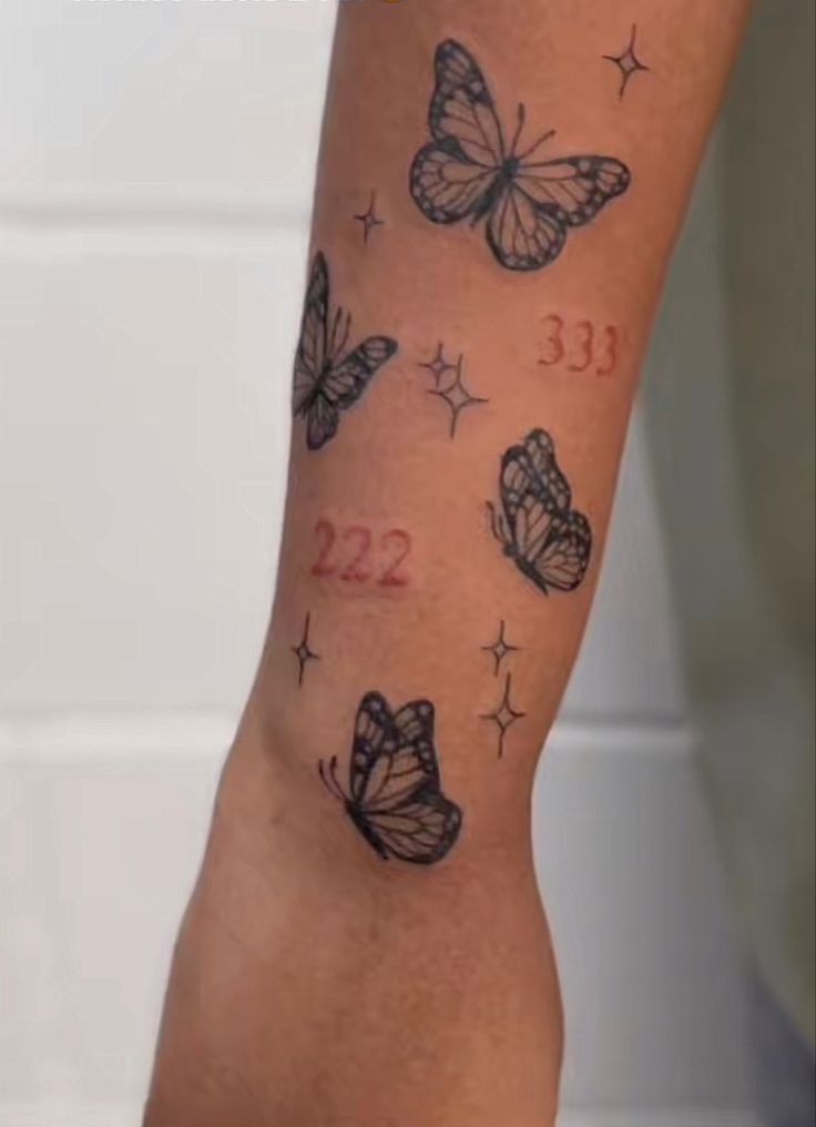 a woman's arm with butterflies and numbers tattooed on the back of her leg