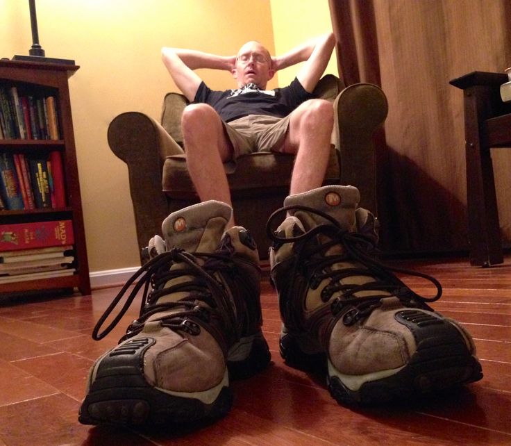 a man sitting in a chair with his feet on the ground and wearing hiking boots