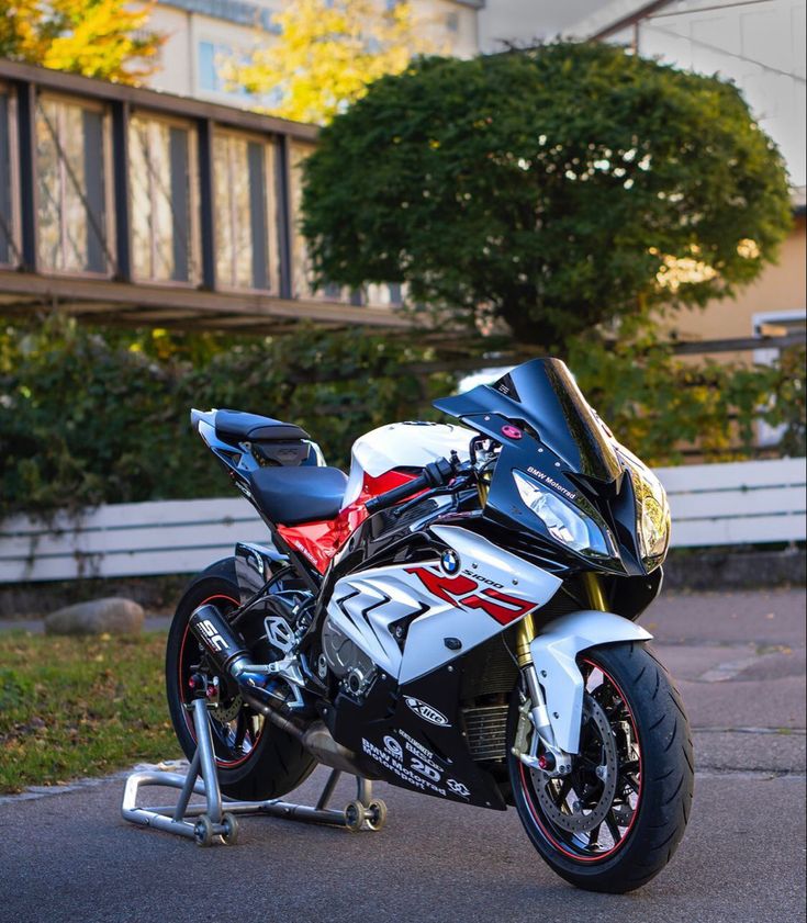 the motorcycle is parked on the side of the road in front of some bushes and trees