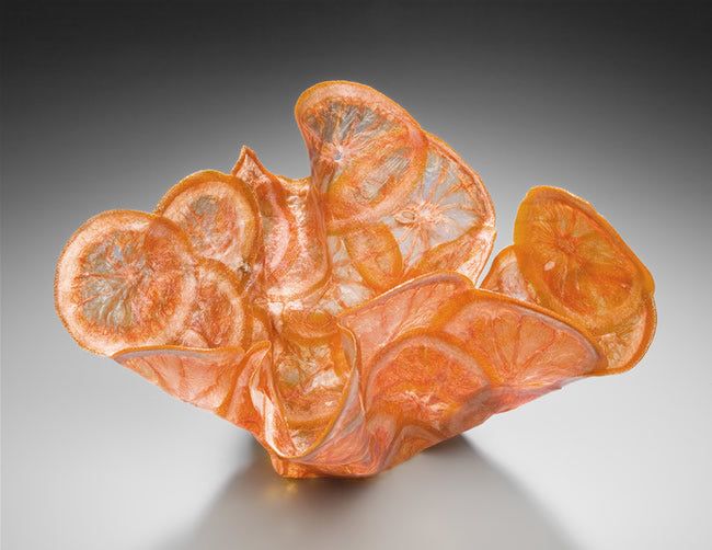 an orange piece of glass sitting on top of a table