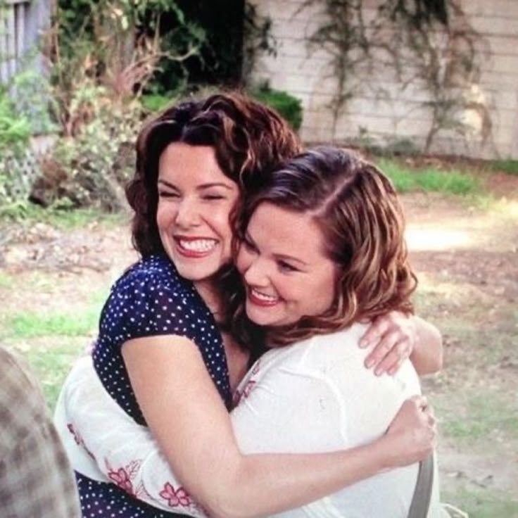 two women hugging each other in the backyard