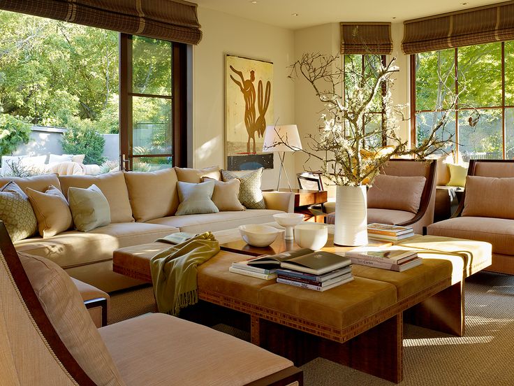 a living room filled with lots of furniture next to two large windows and a painting on the wall