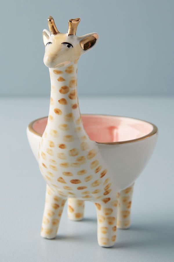 a giraffe figurine sitting in front of a bowl on a table