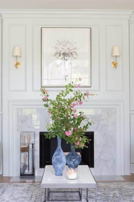 there is a vase with flowers on the coffee table in front of the fire place