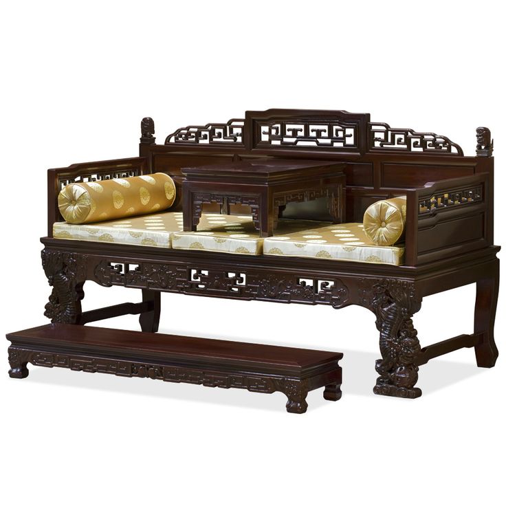 an ornately carved wooden bench and footstool with gold pillows on the seat