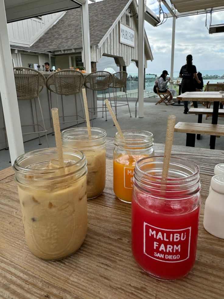 several jars filled with liquid sitting on top of a wooden table next to a building