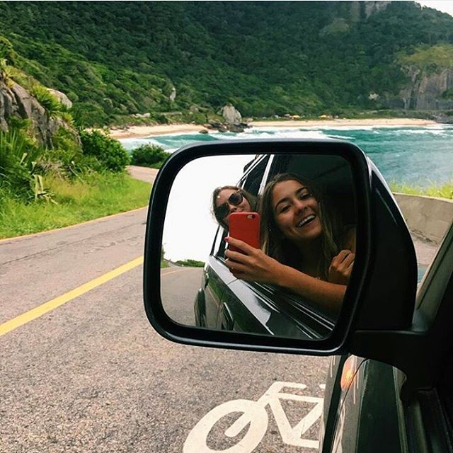 a woman taking a selfie in the side mirror of a car